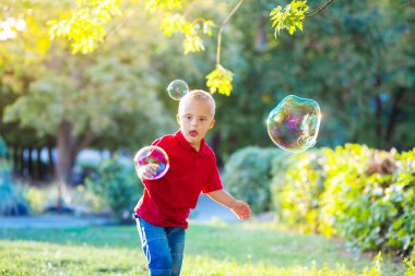 Down sendromlu küçük tatlı bir çocuk parkta büyük sabun köpüğüyle oynuyor. Engelli bir çocuk hasta insanlarla, genetik hastalıklarla, yaşam tarzıyla ilgilenerek sabun topu patlatmak istiyor..