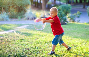 Down sendromlu küçük tatlı bir çocuk parkta büyük sabun köpüğüyle oynuyor. Engelli bir çocuk hasta insanlarla, genetik hastalıklarla, yaşam tarzıyla ilgilenerek sabun topu patlatmak istiyor..
