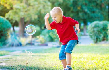 Down sendromlu küçük tatlı bir çocuk parkta büyük sabun köpüğüyle oynuyor. Engelli bir çocuk hasta insanlarla, genetik hastalıklarla, yaşam tarzıyla ilgilenerek sabun topu patlatmak istiyor..