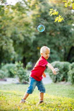 Down sendromlu küçük tatlı bir çocuk parkta büyük sabun köpüğüyle oynuyor. Engelli bir çocuk hasta insanlarla, genetik hastalıklarla, yaşam tarzıyla ilgilenerek sabun topu patlatmak istiyor..