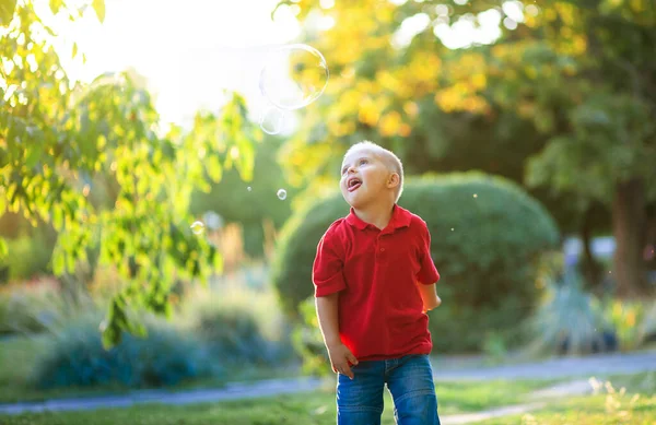 Menino Bonito Com Síndrome Brinca Com Bolhas Sabão Parque Uma — Fotografia de Stock