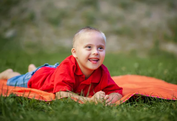 Een Jongen Met Syndroom Ligt Het Park Een Oranje Tapijt — Stockfoto