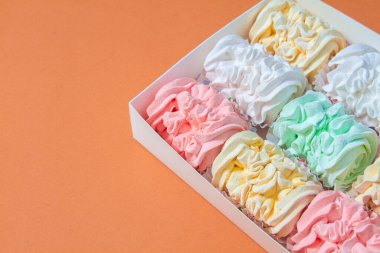 Elma ve nane şekerinden yapılmış ev yapımı marşmelov tabağıyla düz uzanan lokum, turuncu bir kağıdın arka planındaki bir kutuda uzanıyor..