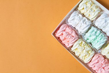 Elma ve nane şekerinden yapılmış ev yapımı marşmelov tabağıyla düz uzanan lokum, turuncu bir kağıdın arka planındaki bir kutuda uzanıyor..