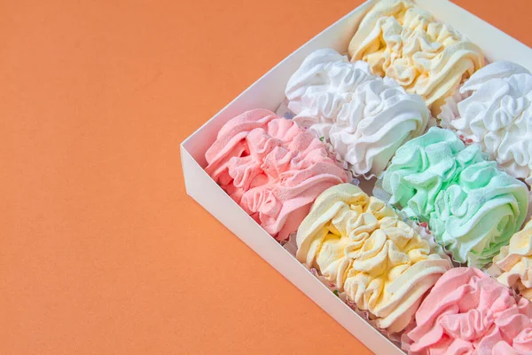 Elma ve nane şekerinden yapılmış ev yapımı marşmelov tabağıyla düz uzanan lokum, turuncu bir kağıdın arka planındaki bir kutuda uzanıyor..