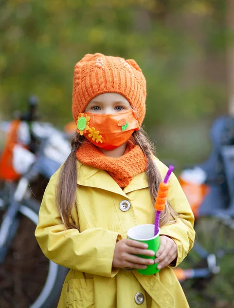 Μικρό Χαριτωμένο Κορίτσι Μια Προστατευτική Μάσκα Προσώπου Και Ένα Πορτοκαλί — Φωτογραφία Αρχείου
