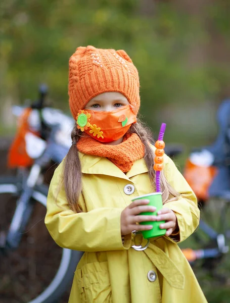 Μικρό Χαριτωμένο Κορίτσι Μια Προστατευτική Μάσκα Προσώπου Και Ένα Πορτοκαλί — Φωτογραφία Αρχείου