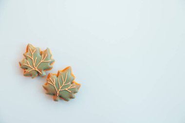 Karmaşık detaylarla kaplı iki yaprak şekilli kurabiye yumuşak renkli bir yüzeyde oturur, sonbaharın özünü yakalar ve güzel işçilik ve tatlılığın tadını çıkarmaya hazır olduğunu gösterir..