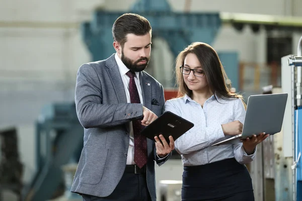Sağlam bir iş adamının portresi elinde dizüstü bilgisayarı ve tableti olan uçak fabrikasındaki fabrika mali raporundan bahsediyor.. 