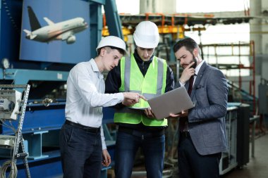 Uçak fabrikasındaki 3 adamın portresi. İki şirket yöneticisi ve gelecek planlarına karar veren bir fabrika işçisi. İş çözümü.