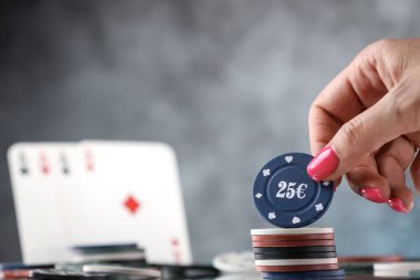 Poker oynayan bir kadının arka planda iskambil kağıtlarıyla yakın plan çekimleri. Çevrimiçi kumar. Bağımlılık. İskambil kağıtları ve poker fişleri düşüyor