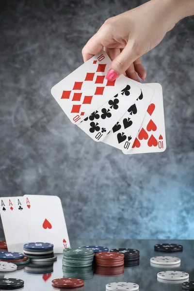 Close up of a woman hand holding poker playing cards, with cards of four aces on the background. Online gambling. Addiction.