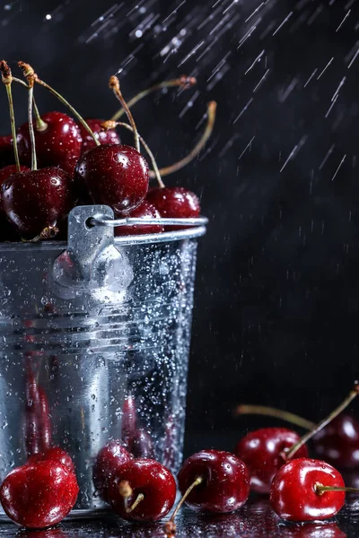 黒を背景にした金属製のバケツの中の赤い甘いチェリー 夏の味 水の下の新鮮な果実は落ちる — ストック写真