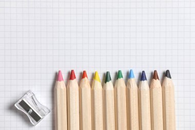 Masada beyaz defter, renkli kalemler ve kalem açacağının düz bir görünümü vardı. Bir okul için hazırlanıyorum. Okula geri dön..