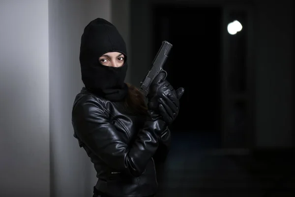 泥棒はアパートに押し入った 黒のジャケットと黒の銃を持つ黒いマスクの女性による住宅強盗 マスクのバーグラー 他人の家に押し入ろうとする仮面の泥棒 — ストック写真