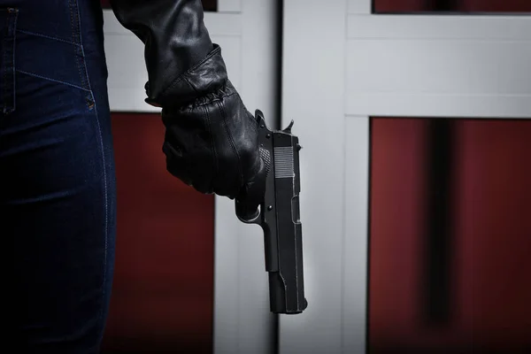 Man in black jacket and black gloves holding black gun. Crime scene.