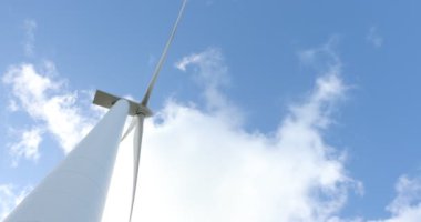 Mavi gökyüzü ve bulutlarla güneşli bir günde rüzgar türbini. Rüzgâr tarlası eko alanı. Yeşil ekolojik enerji üretimi.
