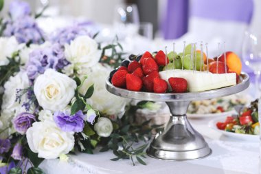 Masada böğürtlenli metal tabak. Çilek, siyah üzüm, yeşil üzüm, elma, kavun ve şeftali. Sağlıklı bir yaşam tarzı. Meyve vitamini.