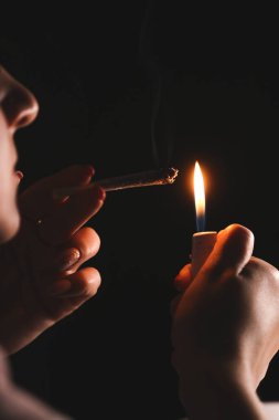 Siyah arka planda sigara içen bir kadın. Esrar içiyorum. Tıbbi kullanım.
