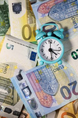 Avro banknotlarının arka planında küçük mavi alarm saati. Mali işler. Finansal kriz. Bankacılık sistemi. Ekonomik bir sorun. Enflasyon. Para yazdırma.