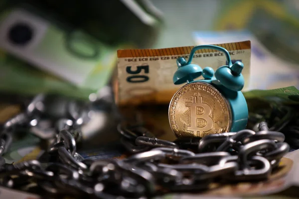Arka planda Bitcoin altın sikkesi ve euro banknotları olan küçük bir retro çalar saat. Yeni mali kaynak. Merkezi olmayan bitcoin ağı. Paranın satın alma gücü