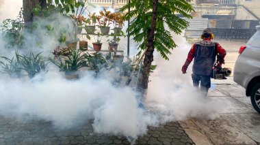 Jakarta, Indonesia - September 26 2025: Fumigation mosquitoes of Zika virus and dengue fever prevention outbreak at home in the small garden in front  kill mosquito carrier of dengue virus.