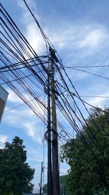 Network of electric cables on electric poles with a cloudy sky in the day with lamp