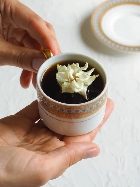 De bloem in de cup. Een beetje wit steeg in een kopje zwarte koffie. Het concept van comfort en schoonheid. — Stockfoto