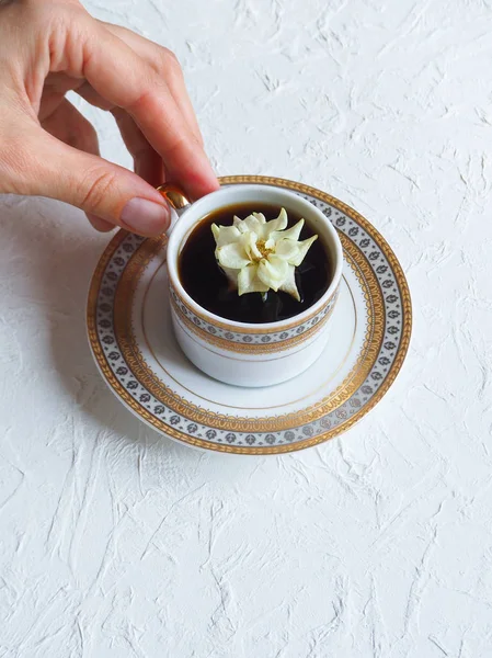 De bloem in de cup. Een beetje wit steeg in een kopje zwarte koffie. Het concept van comfort en schoonheid. — Stockfoto