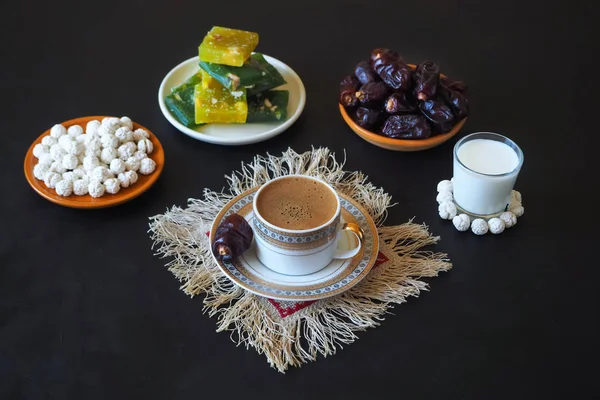 Black coffee and dates on the black table. Sweet food for Ramadan. — Stock Photo, Image