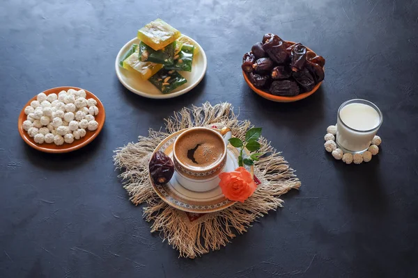 Black coffee and dates on the black table. Sweet food for Ramadan. — Stock Photo, Image