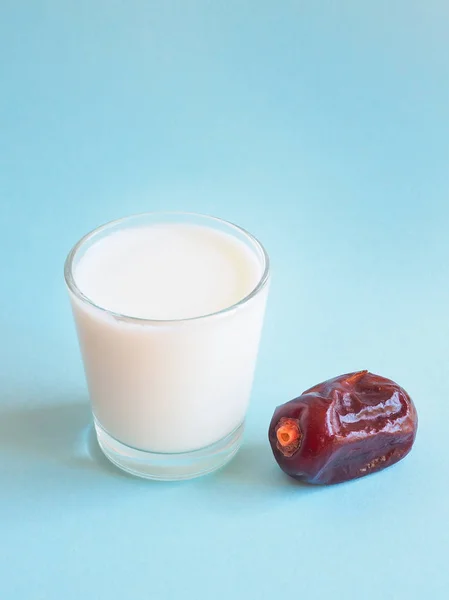 Ett glas mjölk och ett moget datum på en blå bakgrund. Ramadan mat. — Stockfoto