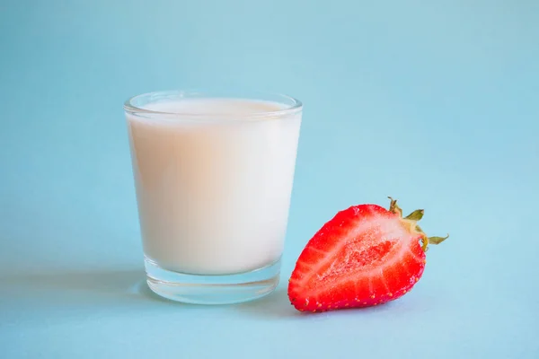 Glas mjölk och mogna jordgubbar på en blå bakgrund. — Stockfoto