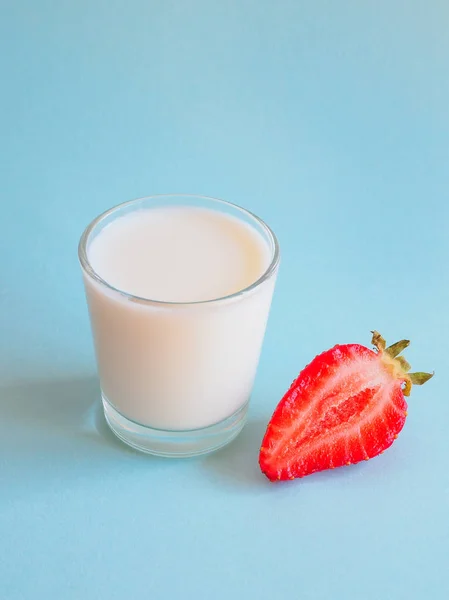 Bicchiere di latte e fragole mature su sfondo blu . — Foto Stock