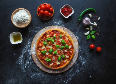 Kiraz domates ve Yeşil fesleğen siyah arka plan üzerine İtalyan pizza Margarita. 