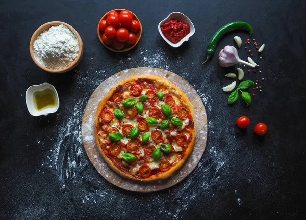 Kiraz domates ve Yeşil fesleğen siyah arka plan üzerine İtalyan pizza Margarita. 