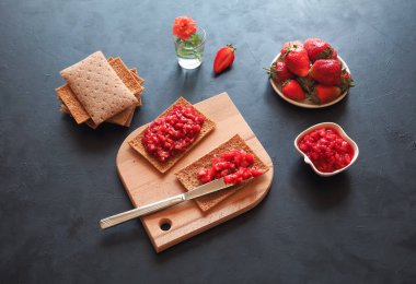 Kızarmış çavdar ekmeği ile Çilek reçel siyah bir masaya. Çilek kahvaltı.