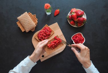 Kızarmış çavdar ekmeği ile Çilek reçel siyah bir masaya. Çilek kahvaltı.