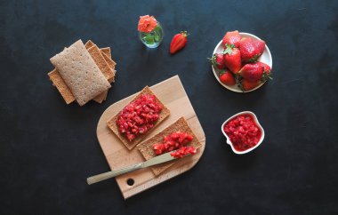 Kızarmış çavdar ekmeği ile Çilek reçel siyah bir masaya. Çilek kahvaltı.