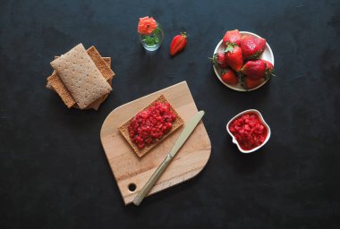 Kızarmış çavdar ekmeği ile Çilek reçel siyah bir masaya. Çilek kahvaltı.