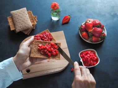 Kızarmış çavdar ekmeği ile Çilek reçel siyah bir masaya. Çilek kahvaltı.