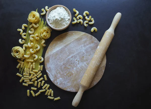 Esparguete macarrão italiano, tagliatelle, fusilli, cavatappi sobre fundo preto. Massa em forma de Crescente . — Fotografia de Stock