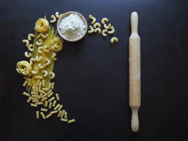 Spaghettis aux pâtes italiennes, tagliatelles, fusilli, cavatappi sur fond noir. Pâtes en forme de croissant . — Photo