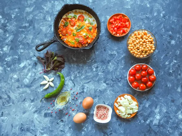 Яичница с горохом и помидорами на старой сковороде и набор овощей на сером фоне . — стоковое фото