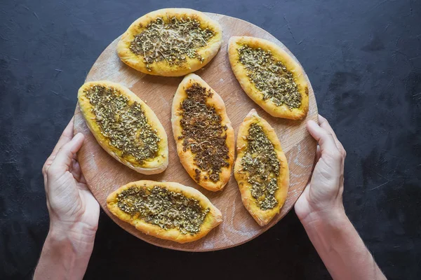 Scones met zatar. Manakish Arabisch op een houten snijplank op een zwarte lijst. Arabische keuken. — Stockfoto