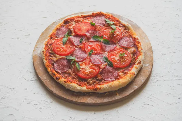 Pizza de pepperoni caseiro em uma mesa de cozinha branca . — Fotografia de Stock