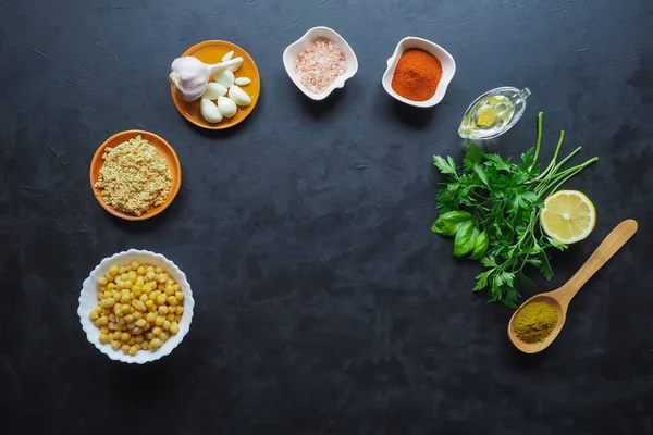 Zutaten für Hummus auf dem schwarzen Küchentisch. Ansicht von oben. — Stockfoto