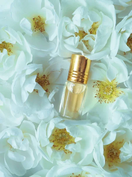 Çiçek bir arka plan üzerinde mini bir şişede gül yağı.