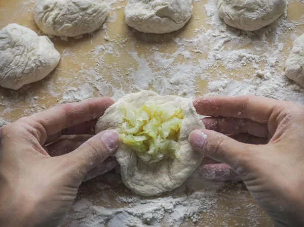 Torte fatte in casa della pasta nelle mani delle donne. Il processo di fare torte con pasta di cavolo a mano . — Foto Stock