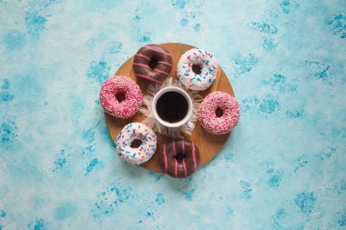 Bir fincan kahve ve çörek tatlılar mavi bir tablo.
